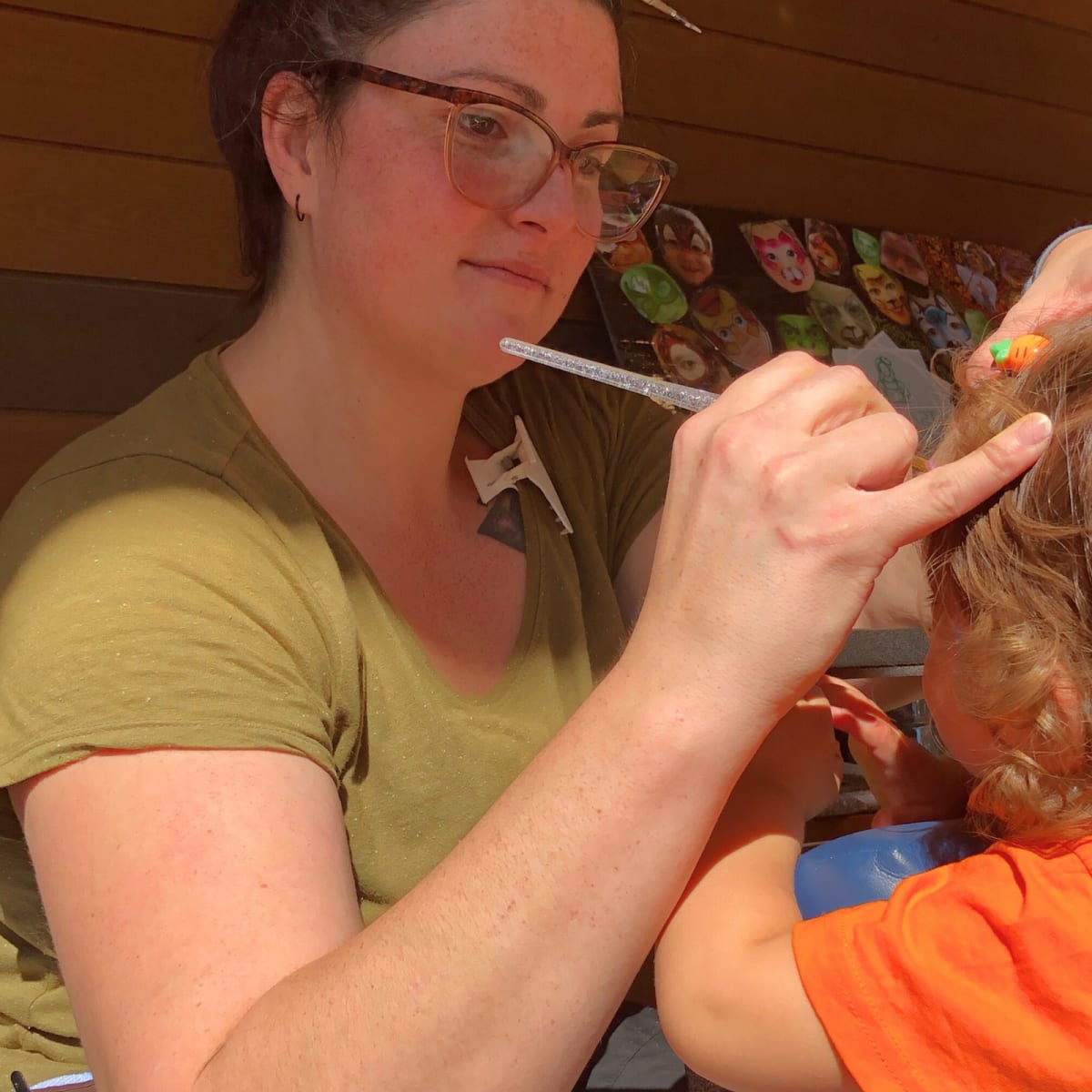 A woman paints a child's face at the “Festival des Couleurs” in Parc régional Montagne du Diable.