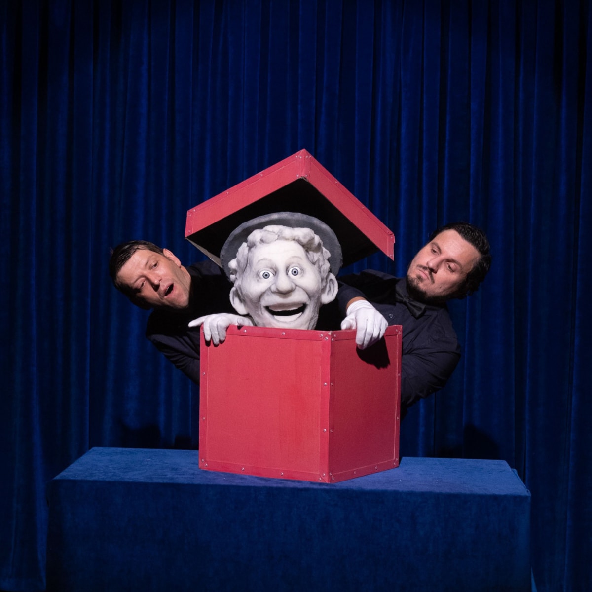 Festival international des arts de la marionnette - A puppet is in a red box. Two men stand next to it.
