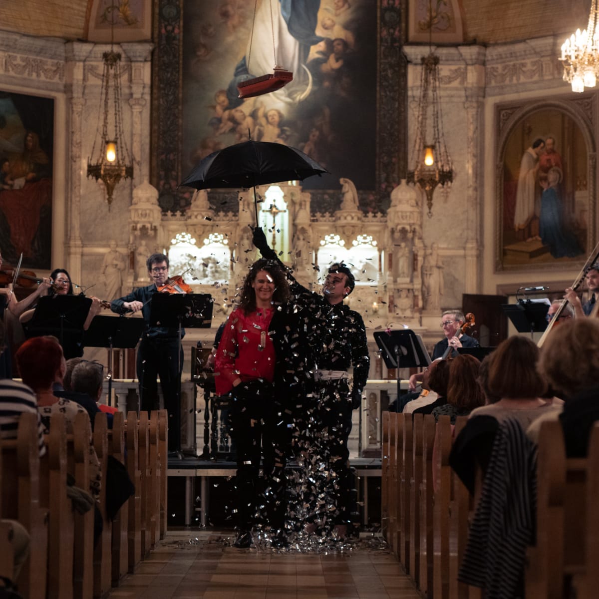Montreal Baroque Festival - Concert inside a church. A man holds an open umbrella with falling confetti.
