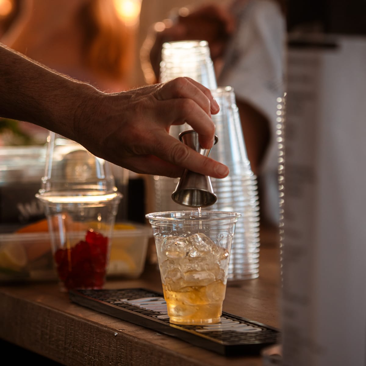 Festival Parasol - Une main verse du liquide dans un verre rempli de glace