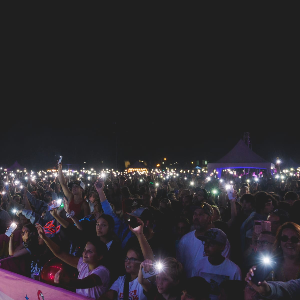 A crowd with their phone lights on during a show at the Festival POP ton été