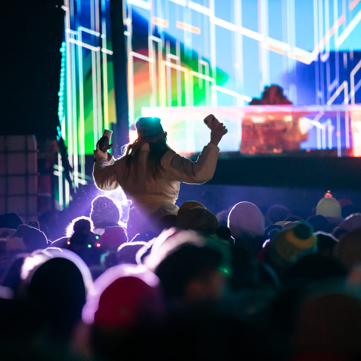 Young woman dancing in front of a DJ booth.