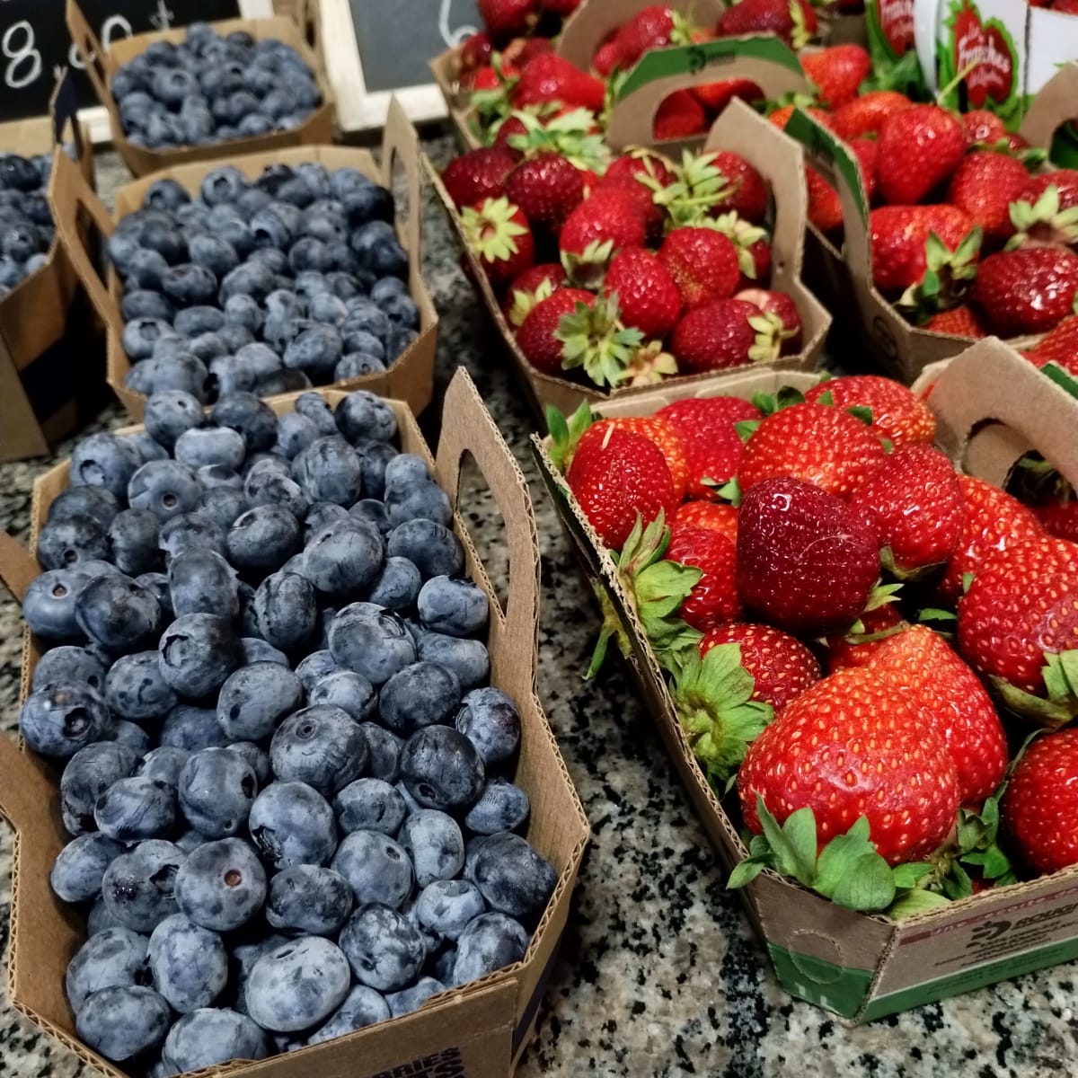Baskets of blueberries and strawberries on a counter.