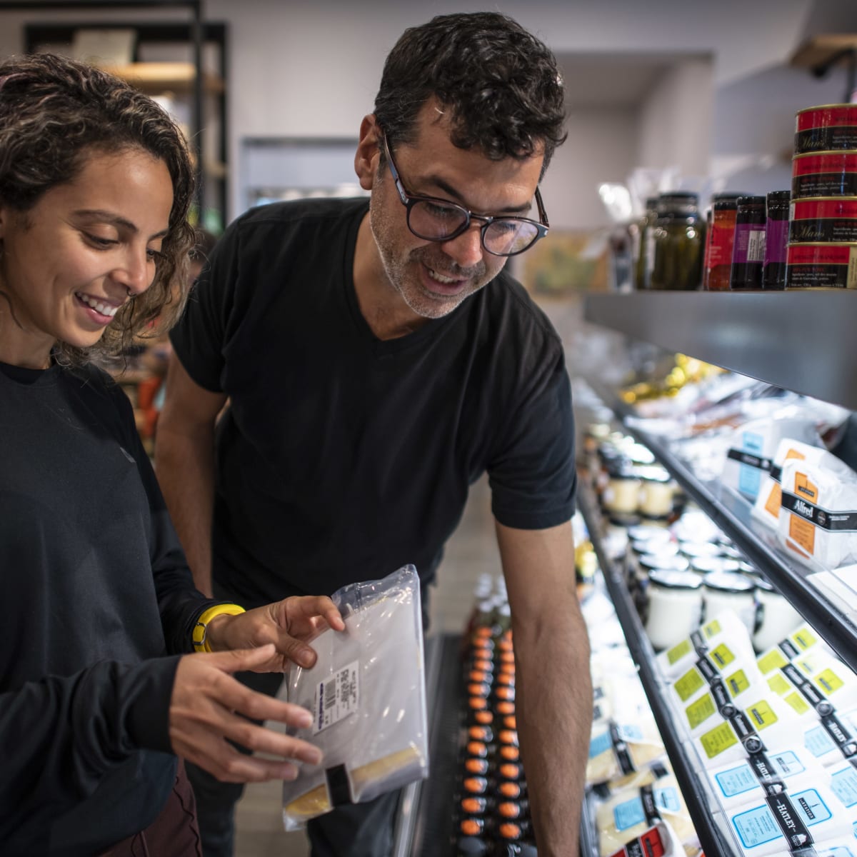 Two people looking at cheeses.