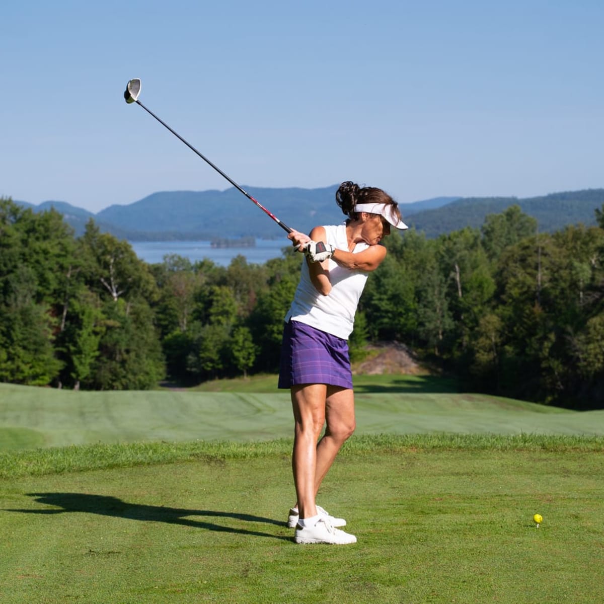 A woman takes a swing on a golf course in the Laurentians in the summer.