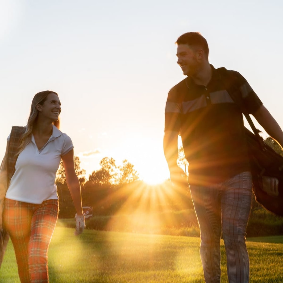 Two golfers walking together on a golf course in the Laurentians at sunset.