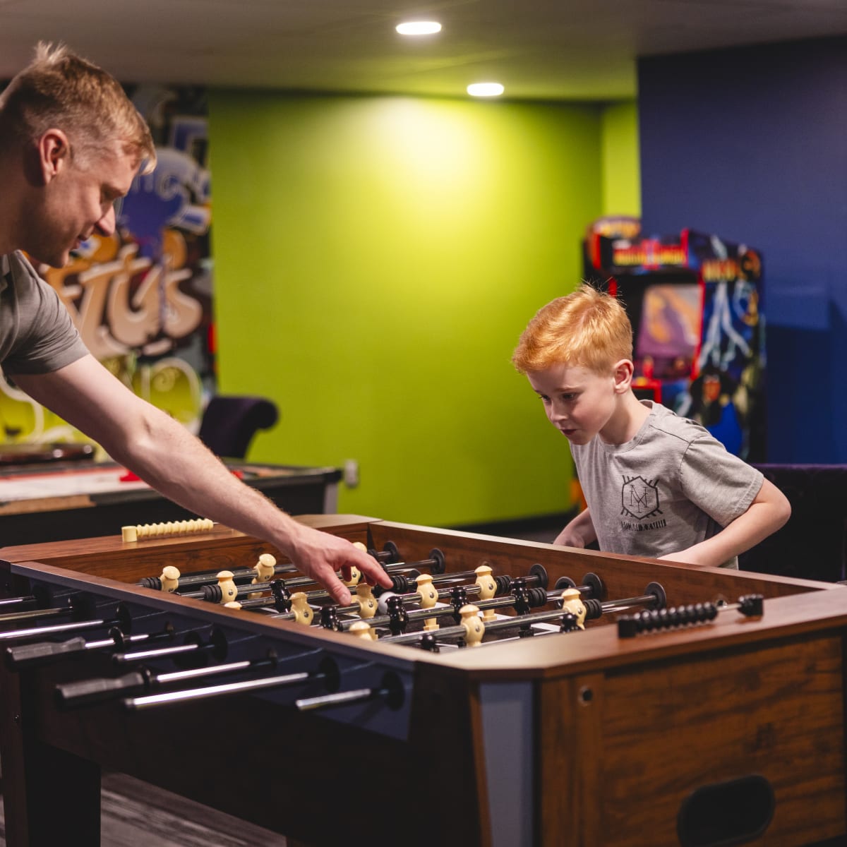Hôtel Universel Rivière-du-Loup - A man and a boy playing foosball in a playroom
