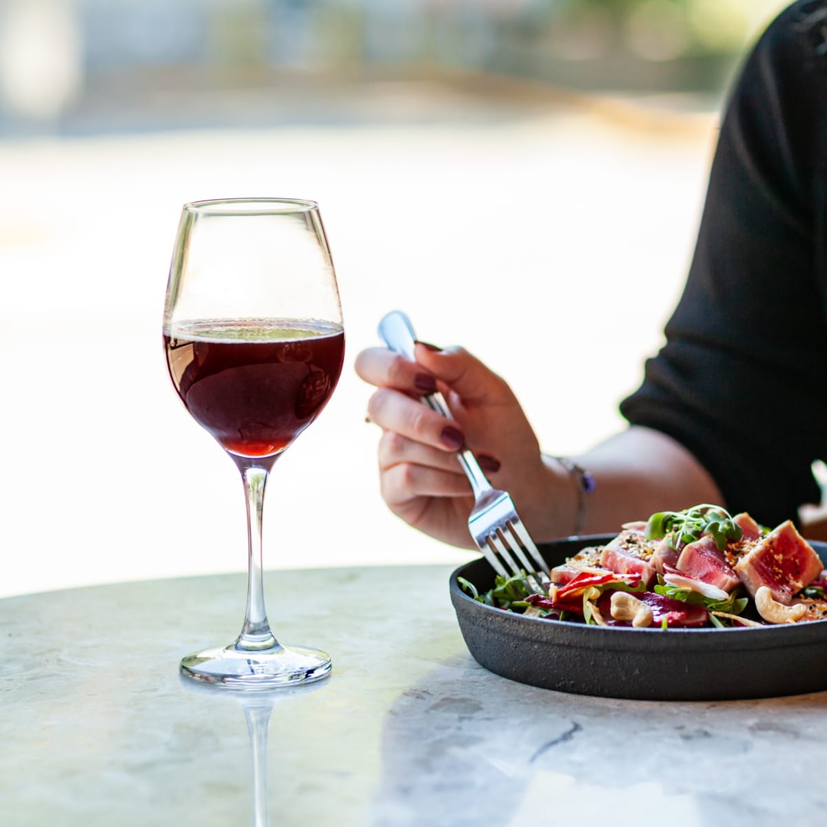 Woman tasting red wine and a dish at a hotel.