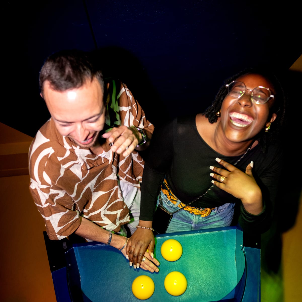 La Boîte à Questions – Quiz Room Montréal - Two people happily leaning over an interactive machine