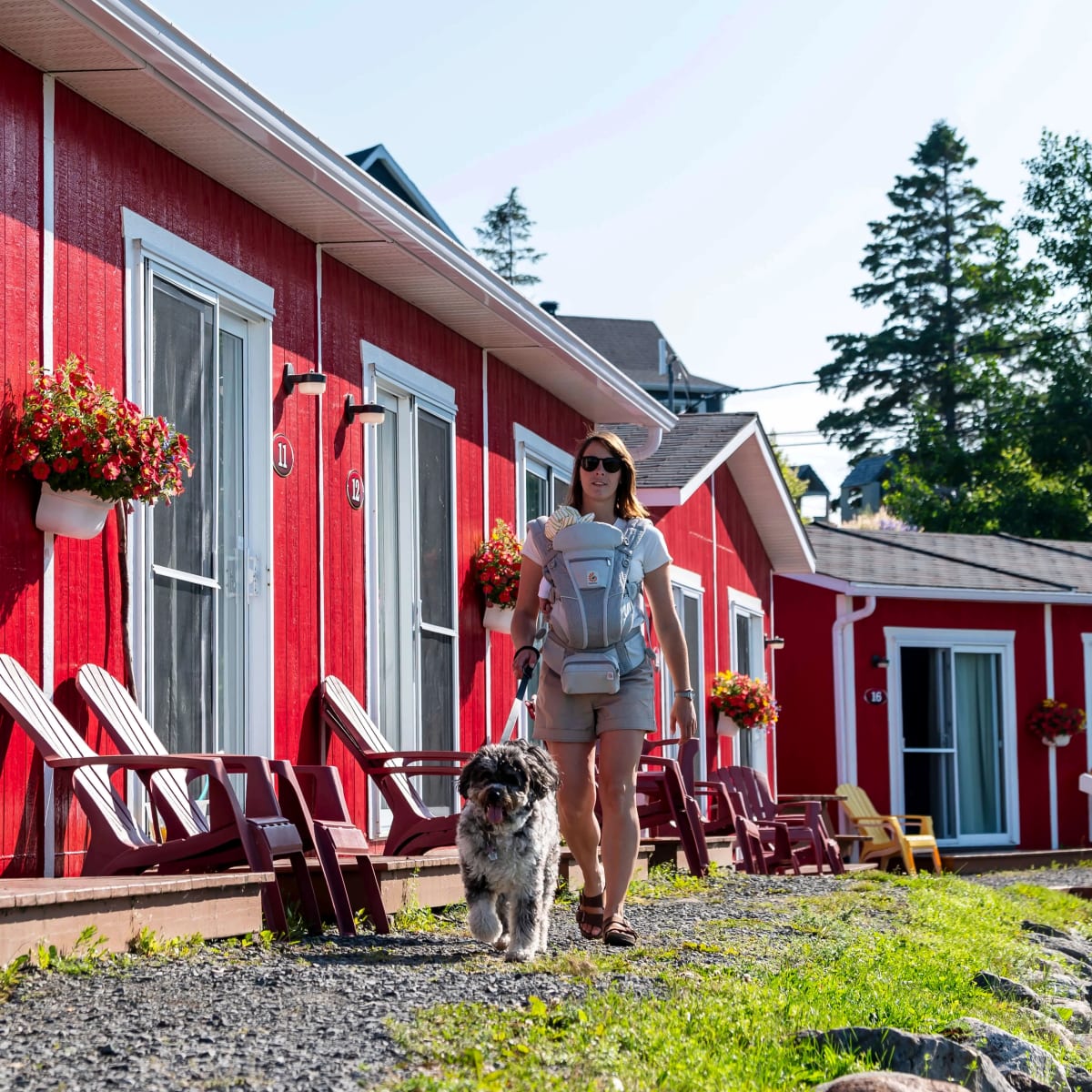 Une femme avec son bébé et chien devant des cabines rouges du Navigateur Ste-Luce.