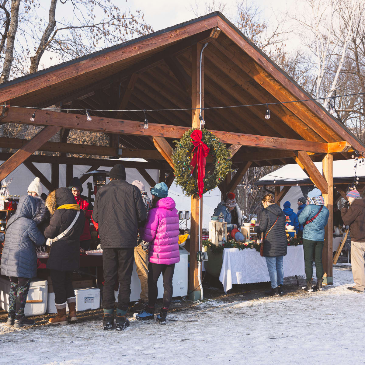 Des personnes à un kiosque extérieur d'un Marché de Noël en Memphrémagog.