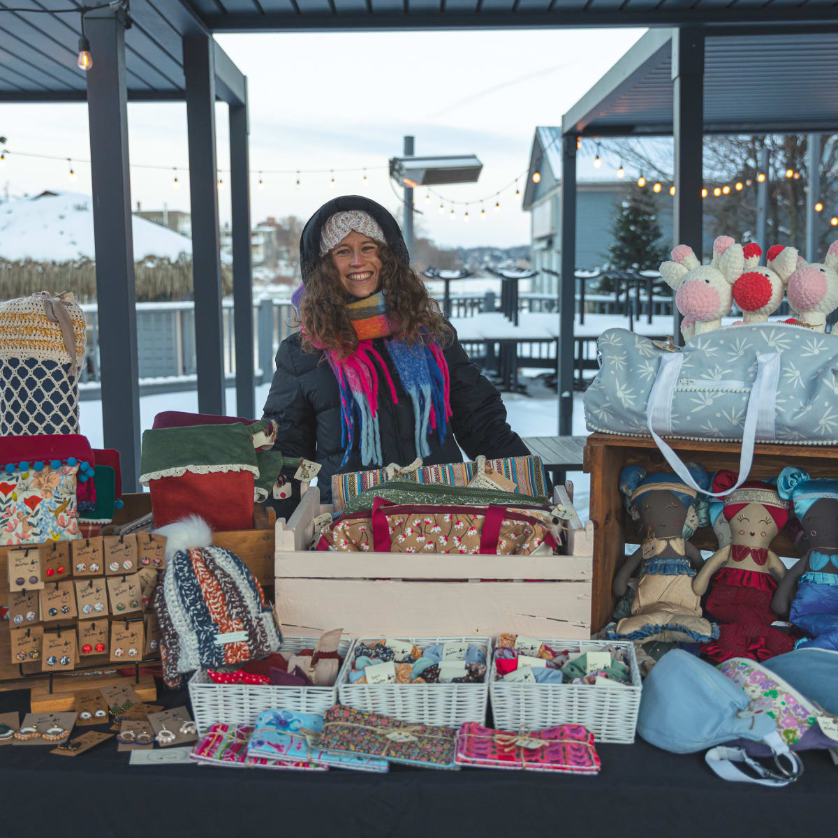 Une vendeuse derrière son kiosque à un Des personnes à un kiosque d'un Marché de Noël en Memphrémagog.
