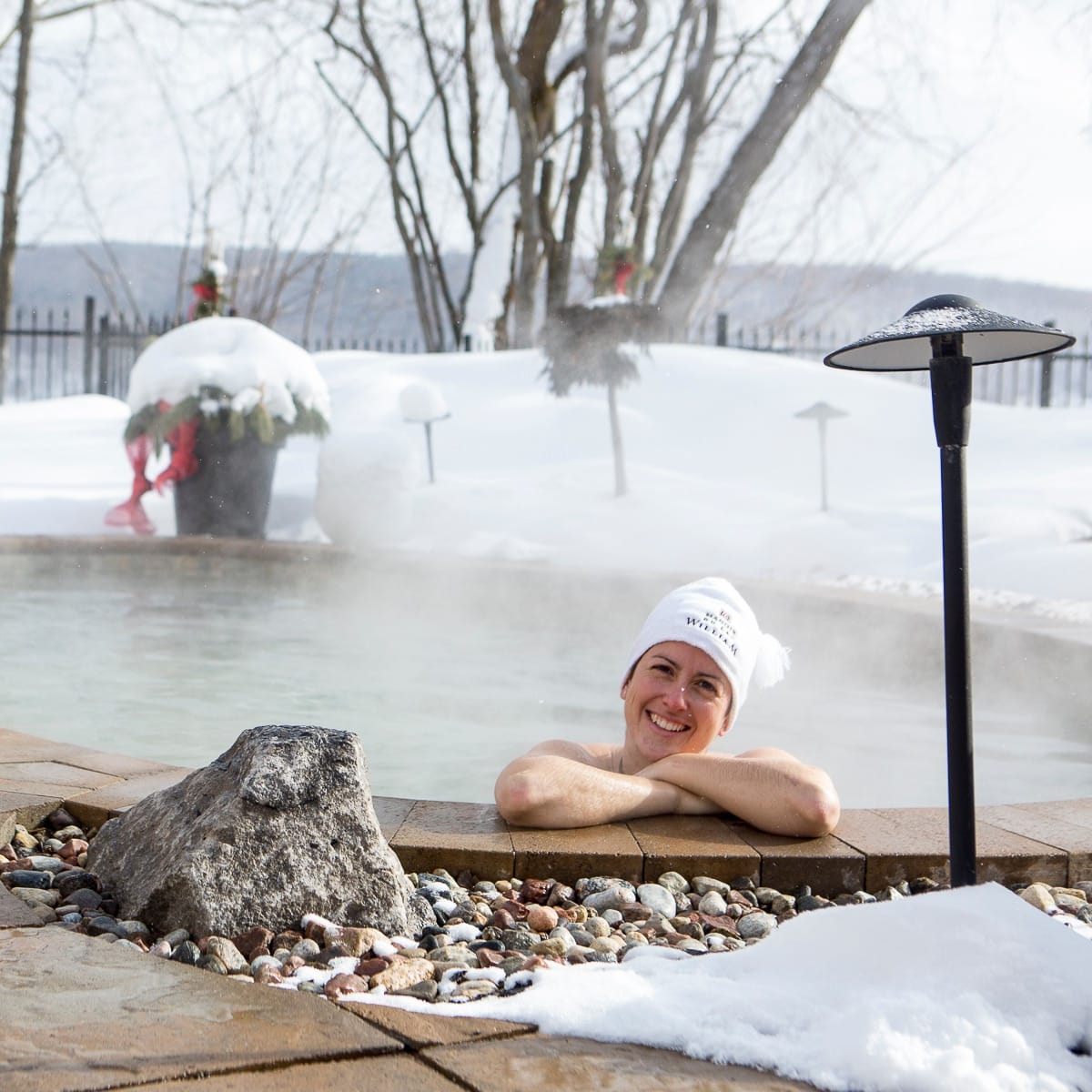 Woman in the outdoor spa at Manoir du Lac William in winter.