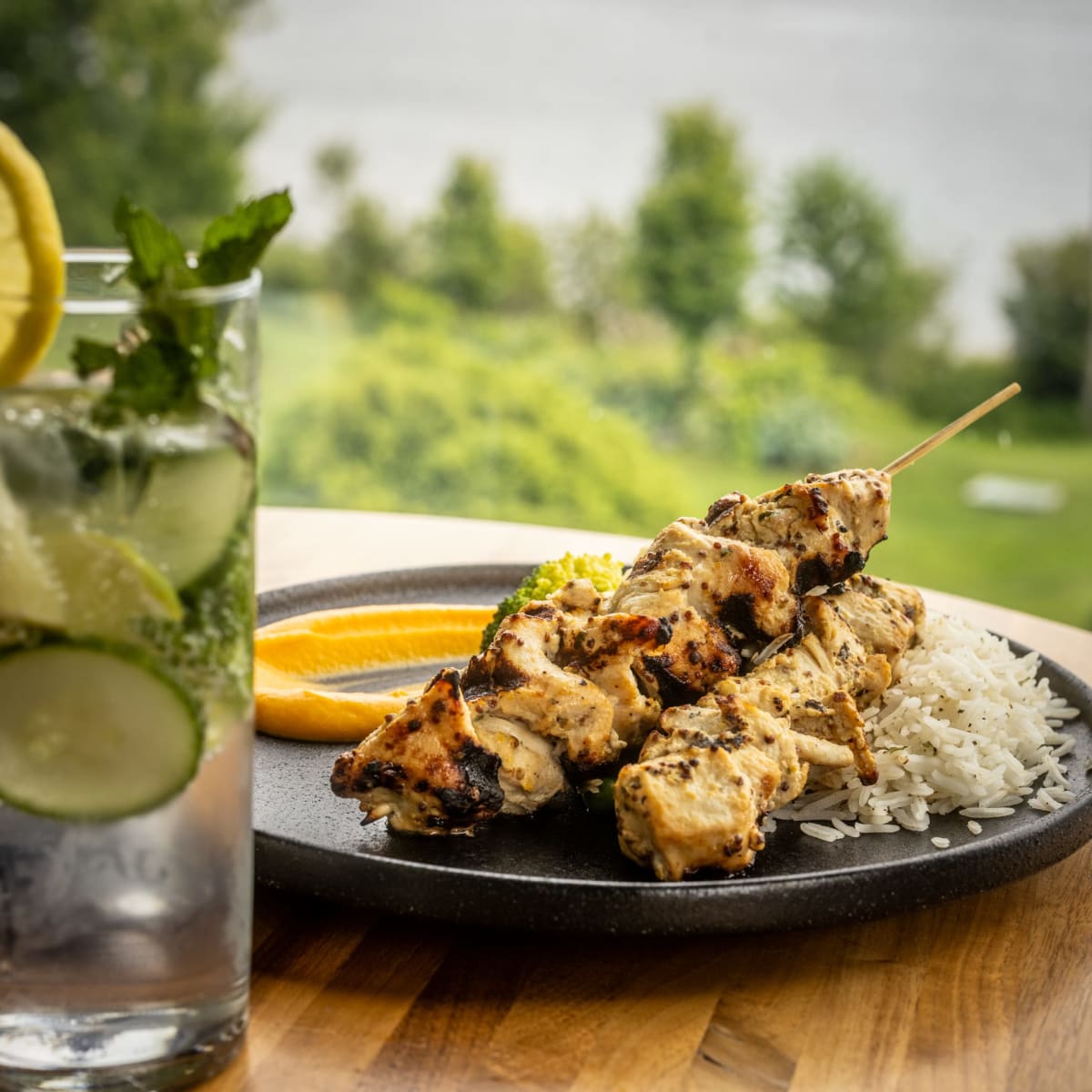 Assiette de brochettes panées accompagnée d'un cocktail avec tranches d'agrumes.