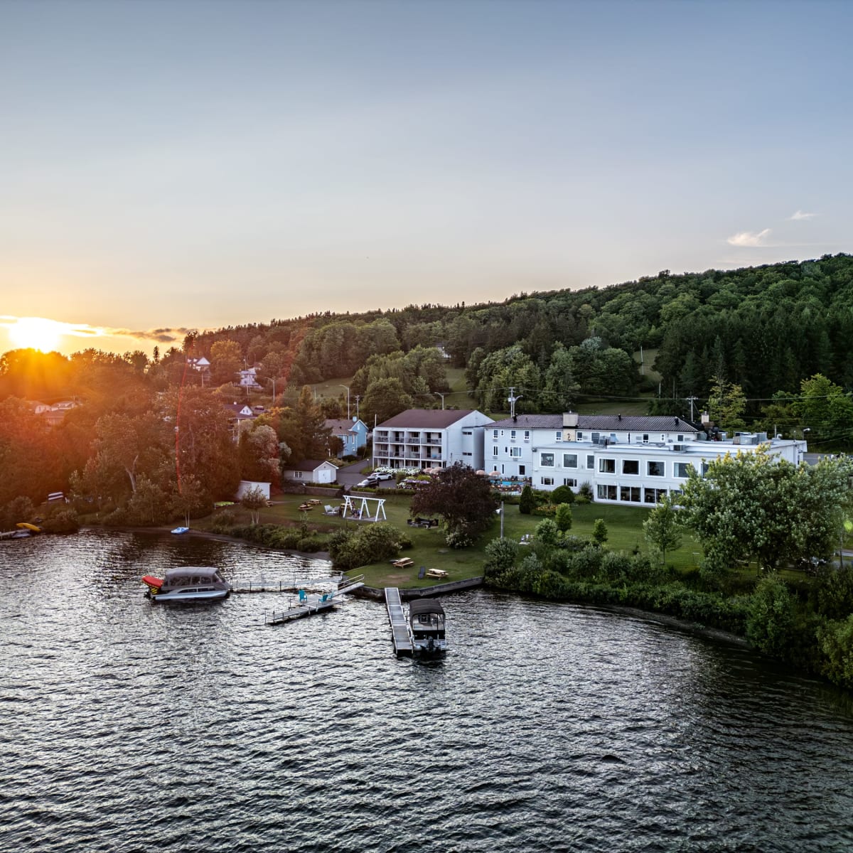 Vue d'ensemble du Manoir Lac-Etchemin et du lac au coucher de soleil.