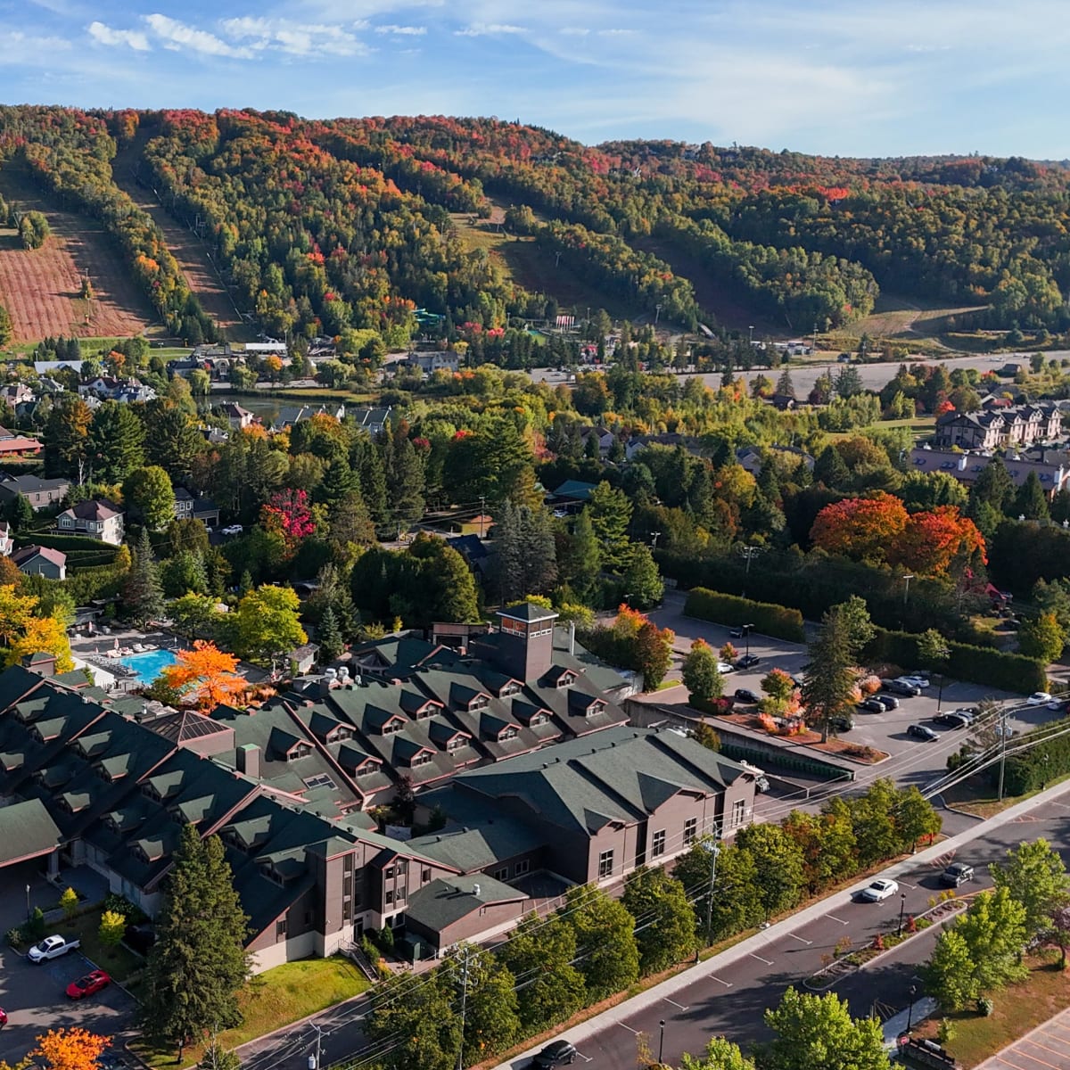 Vue aérienne de l'Hôtel-Manoir Saint-Sauveur en début d'automne, avec le mont Saint-Sauveur en arrière-plan.