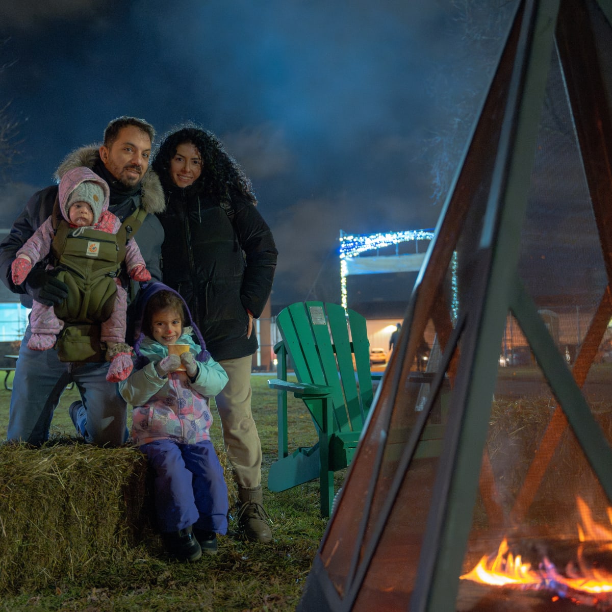 A family warms up by a campfire.