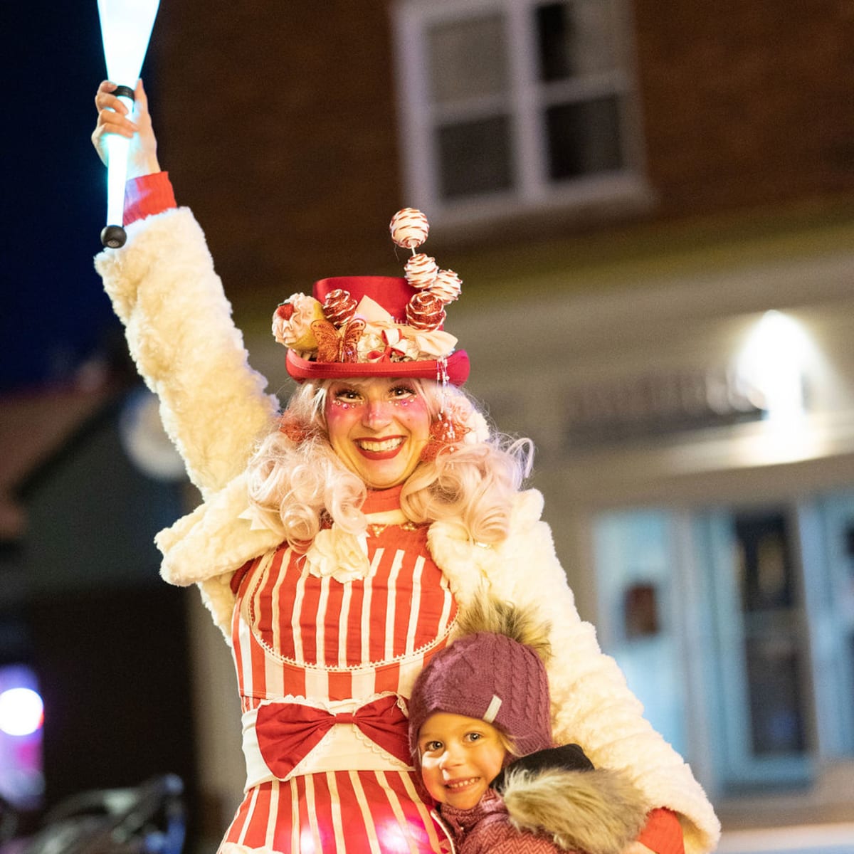 An eccentric juggler gives a hug to a little girl.