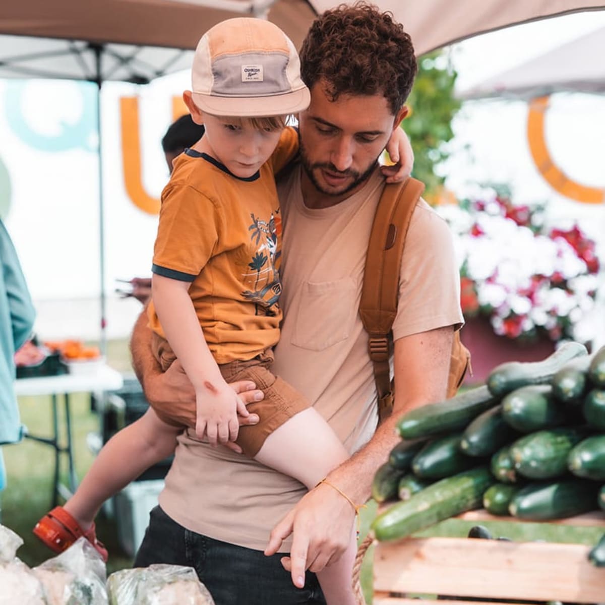 A father shows his son the vegetables at the market