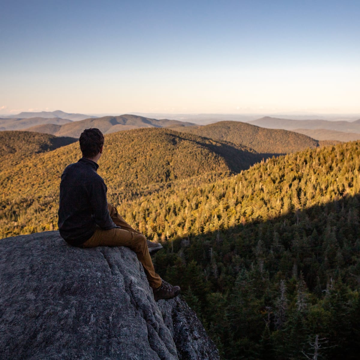 All the colors of fall in Brome-Missisquoi - Hiker admiring the foliage at the top of Mont Sutton