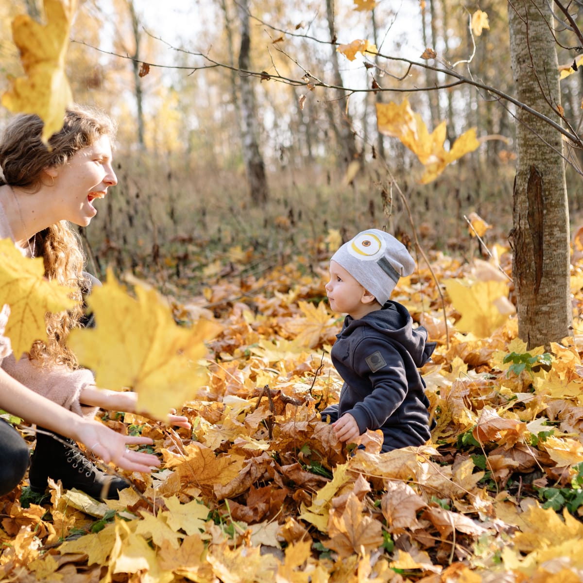 Mère et un enfant en train de jouer dans les feuiles d'automne.