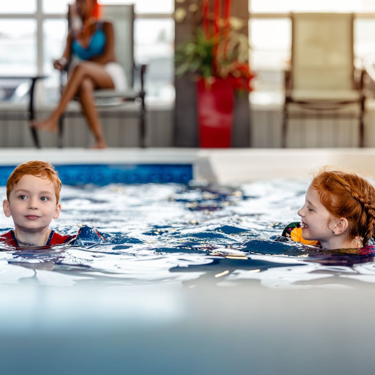 Two kids in a pool at a hotel.