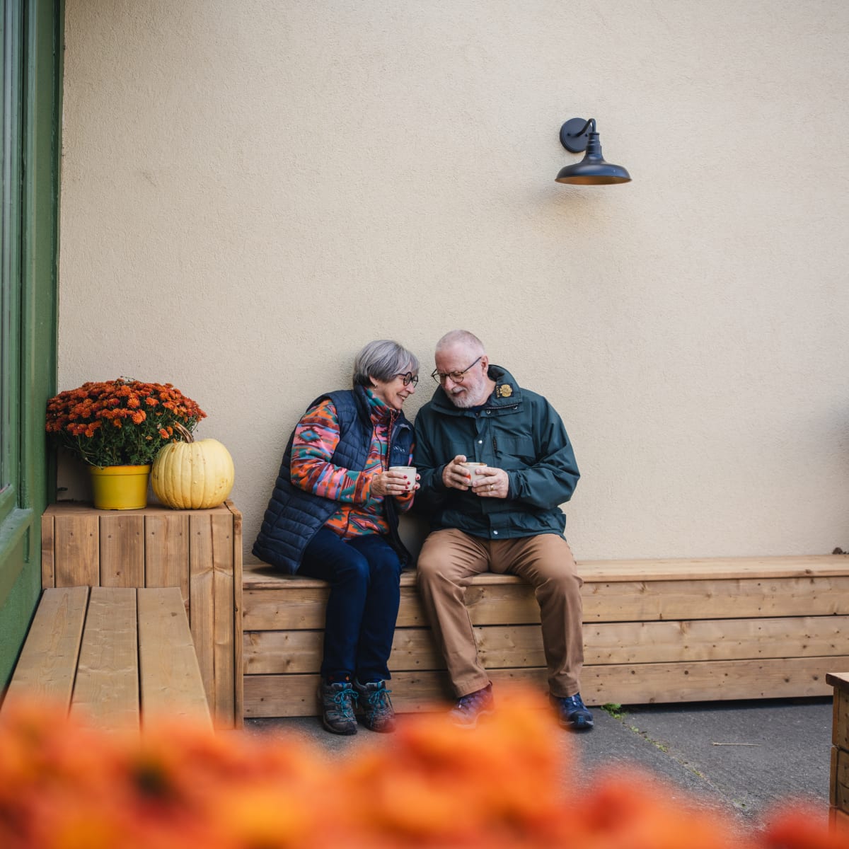 Municipalité d'Orford - A couple sitting on a wooden bench outside in autumn