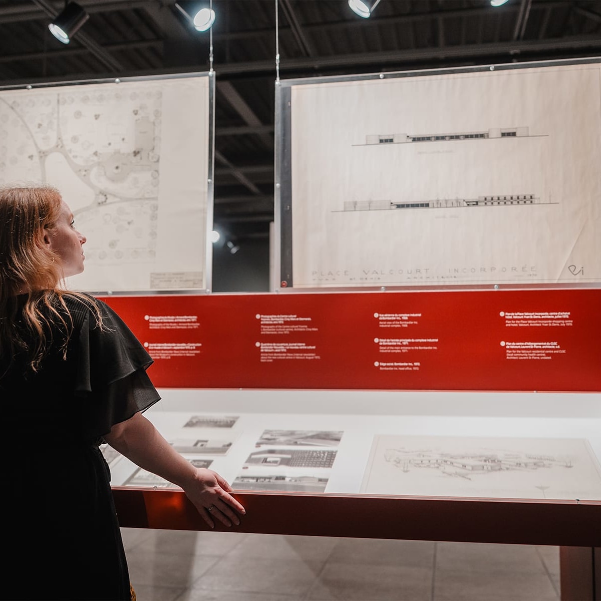 Visiteuse devant des panneaux d'interprétation de l'exposition "Territoires d’identité" au Musée de l'ingéniosité J. Armand Bombardier