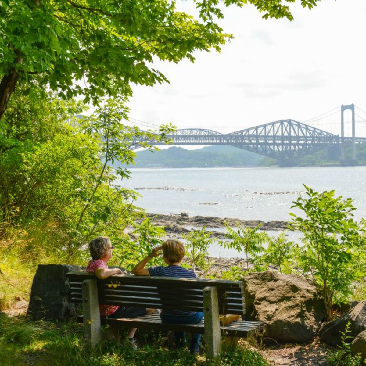 Deux personnes assises sur un banc l'été au Parc de la plage Jacques-Cartier.