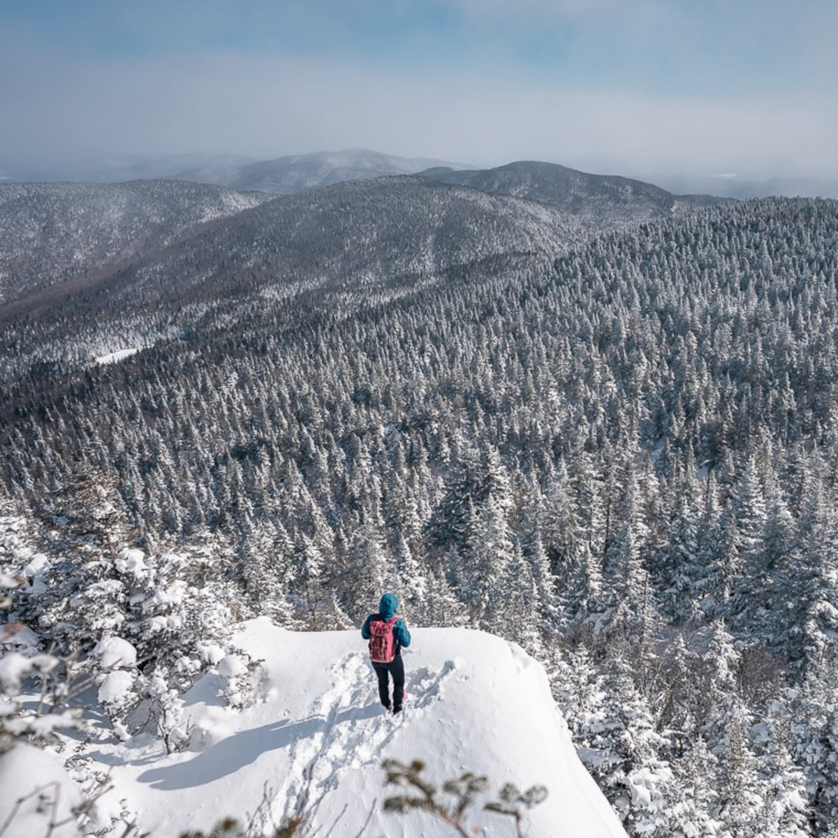 Hiker at the summit in winter at Parc d'environnement naturel de Sutton.