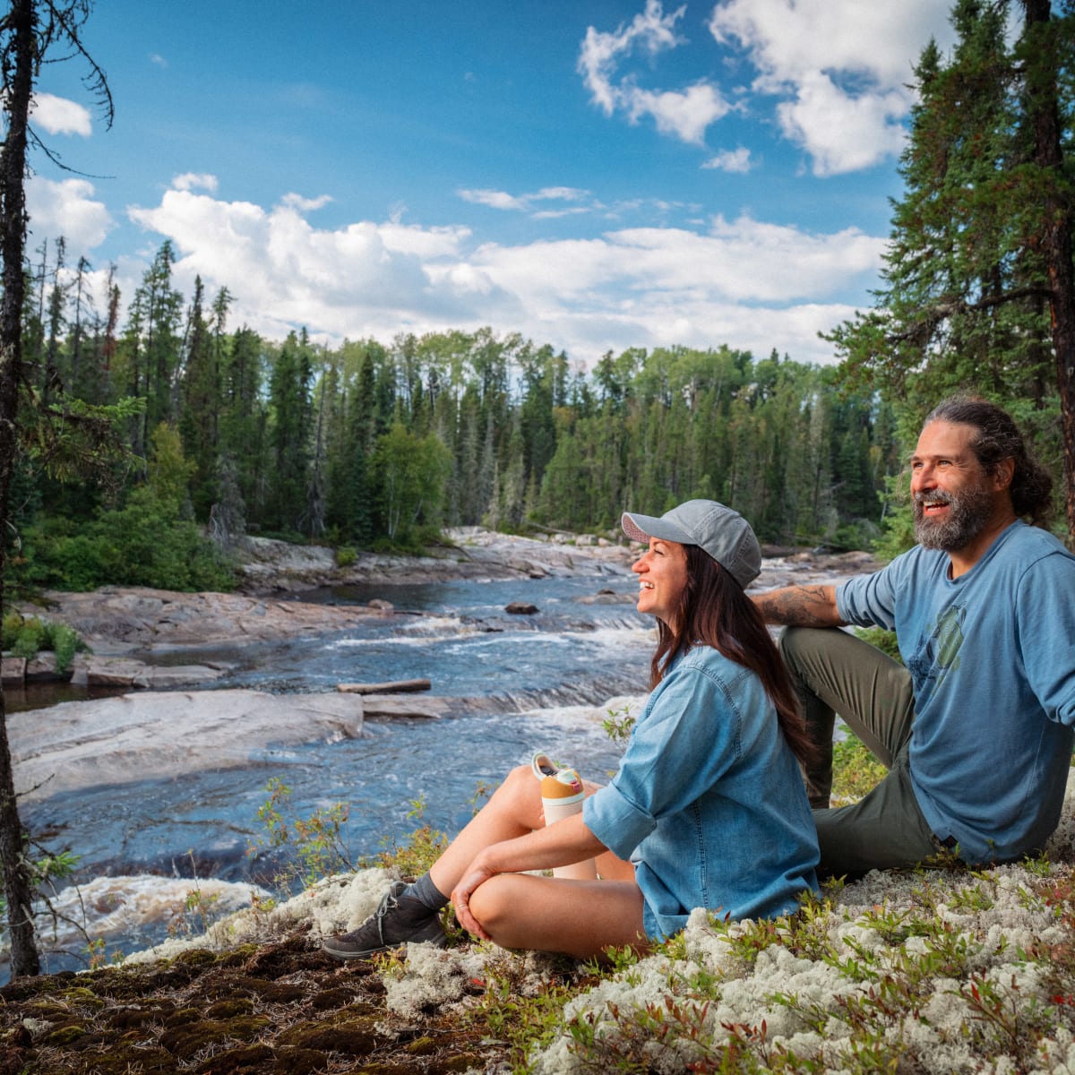 A man and a woman sitting by the river in the summer. 