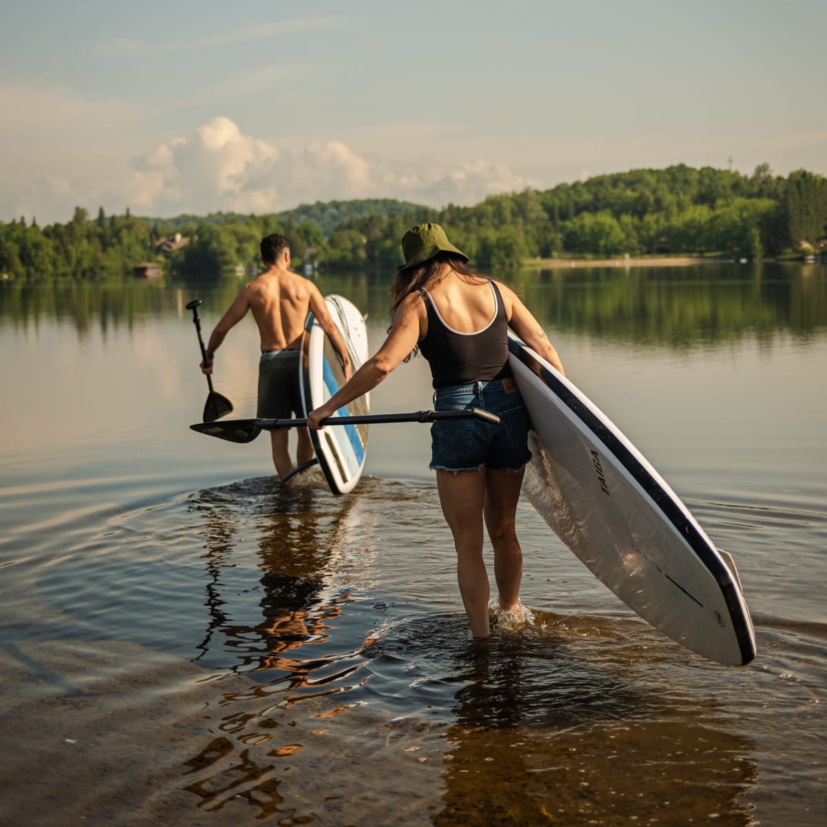 Deux personnes avec leur planche à pagaie au Parc régional Sainte-Agathe-des-Monts.