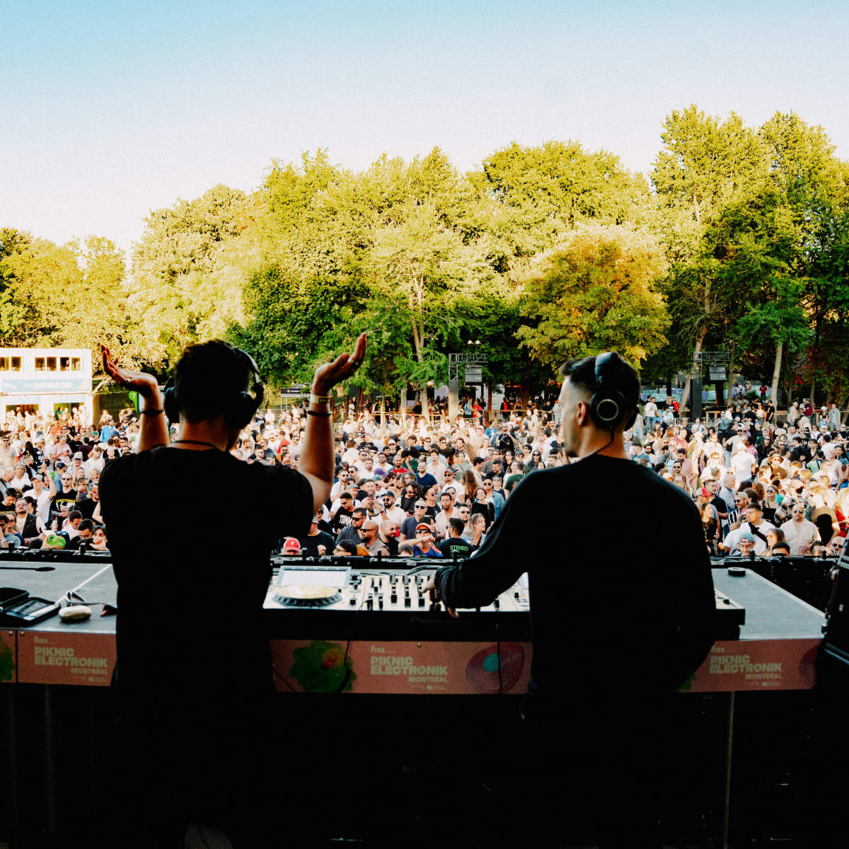 Two DJs on stage in front of the crowd.