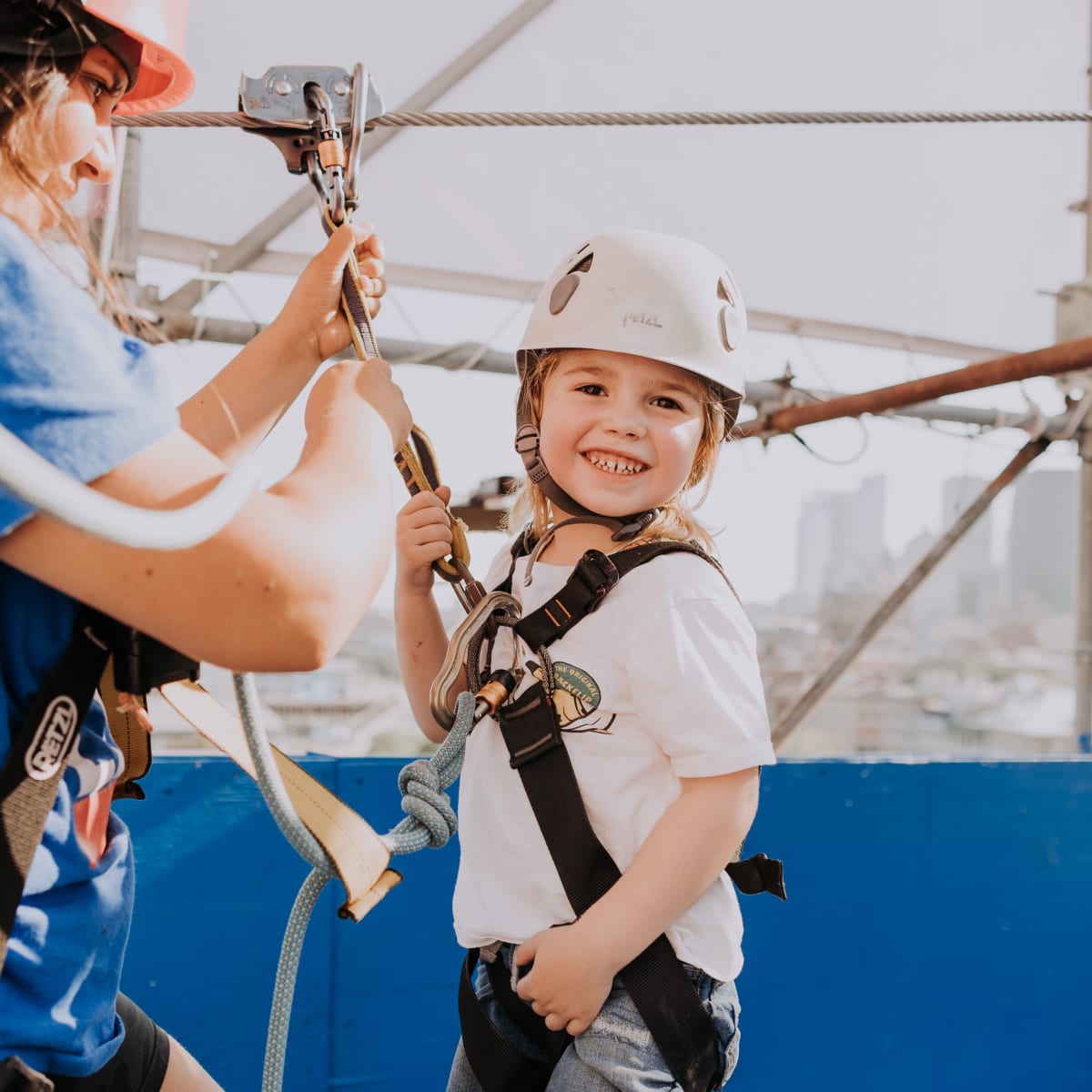 Jeune fille souriant, casque sur la tête, avant une descente en tyrolienne