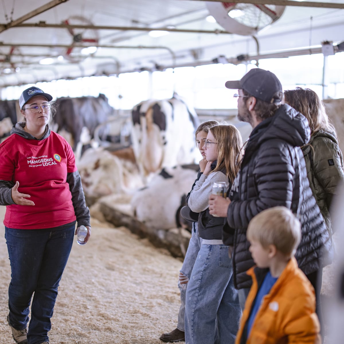 Famille qui écoute une présentation dans une ferme laitière lors des Portes ouvertes sur les fermes du Québec.