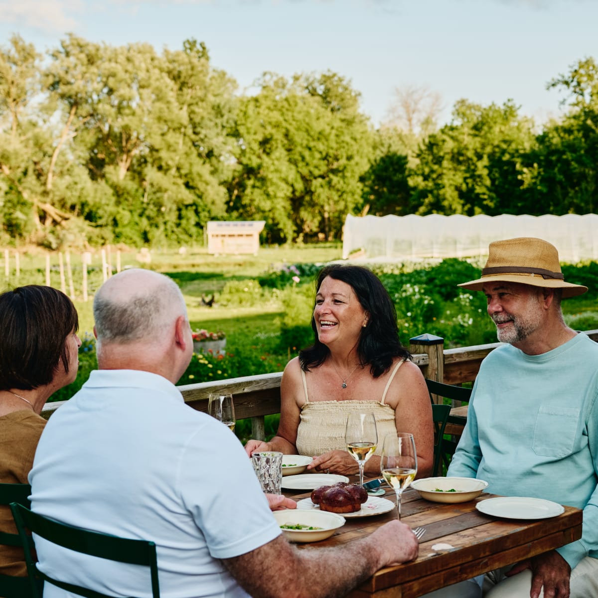 Groupe de 4 adultes assis autour d'une table dans un vignoble.