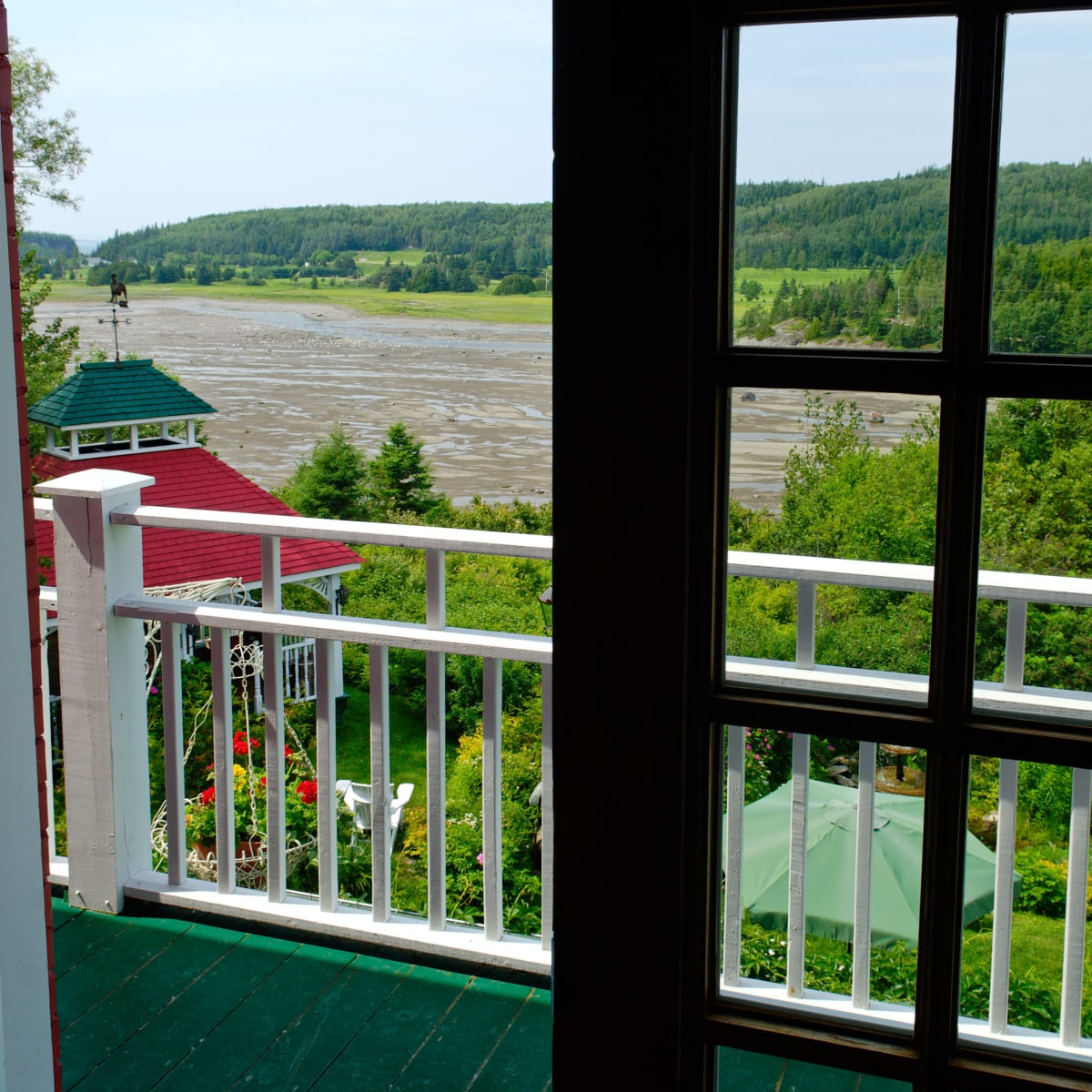 A window with open shutters on a gray summer day by the river.