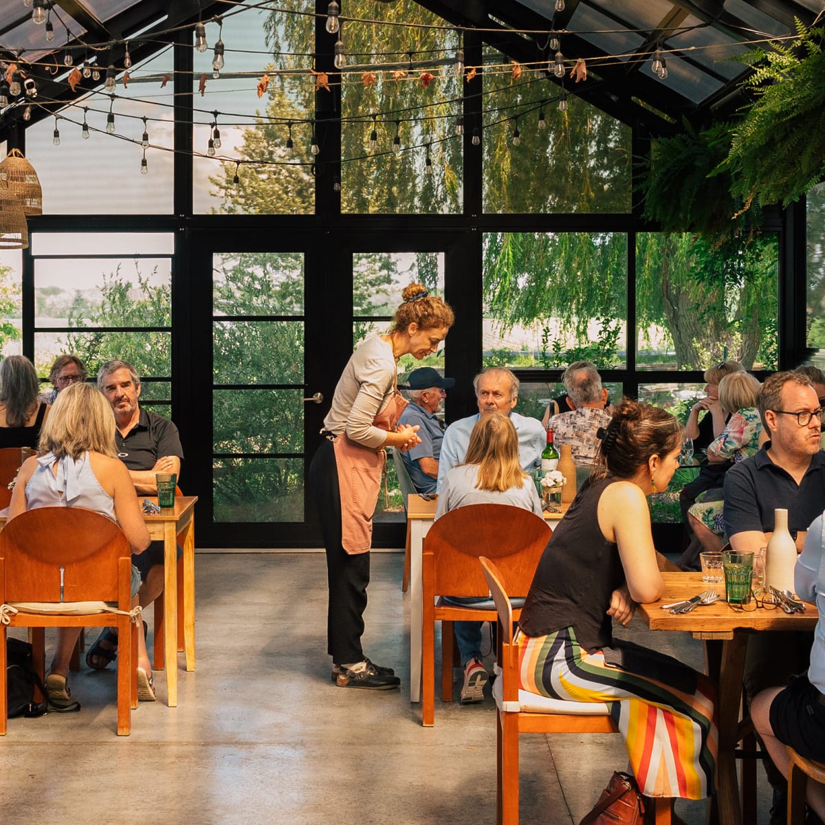 Personnes qui mangent dans la serre d'un restaurant champêtre.