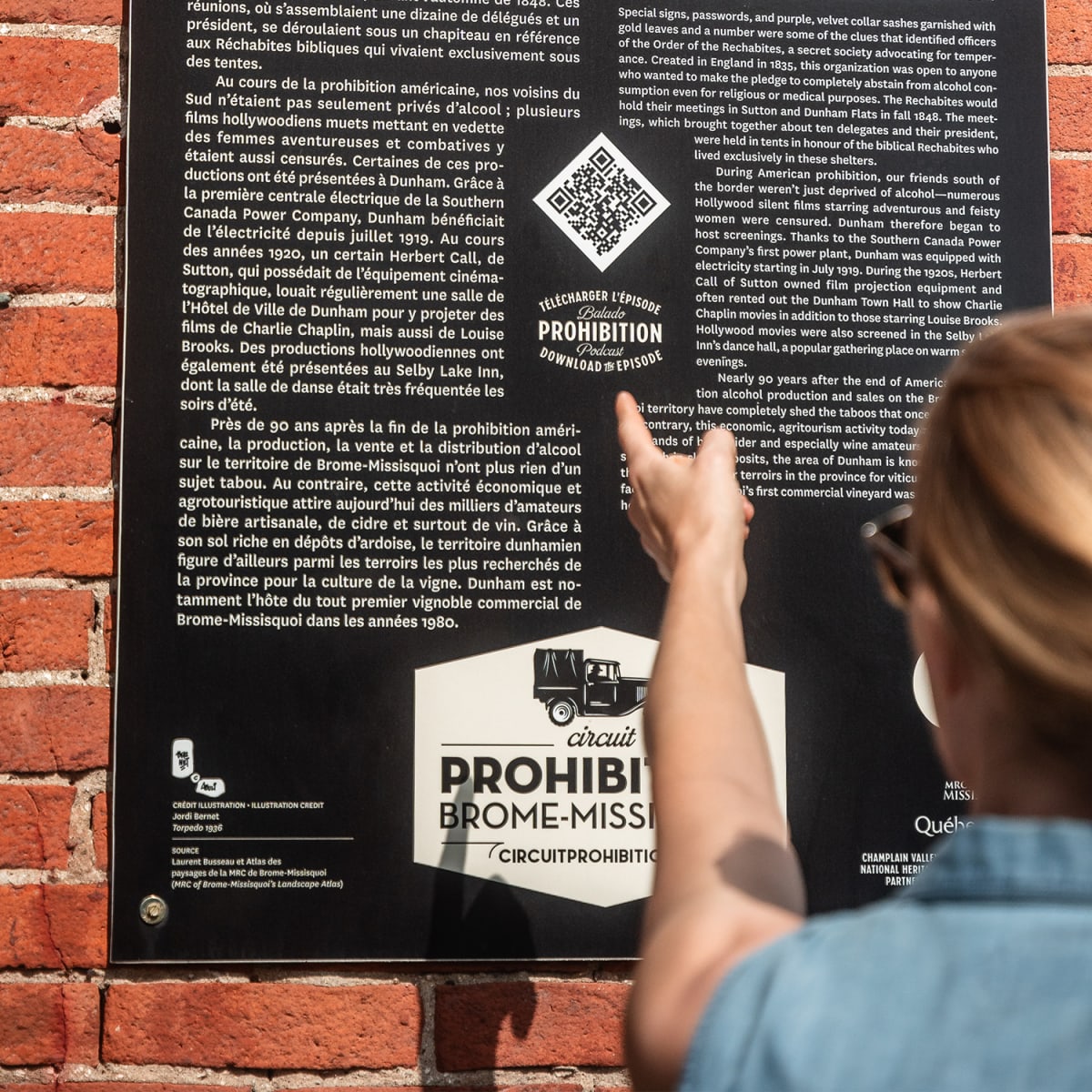 Woman reading a panel on the Prohibition Heritage Trail in Brome-Missisquoi.