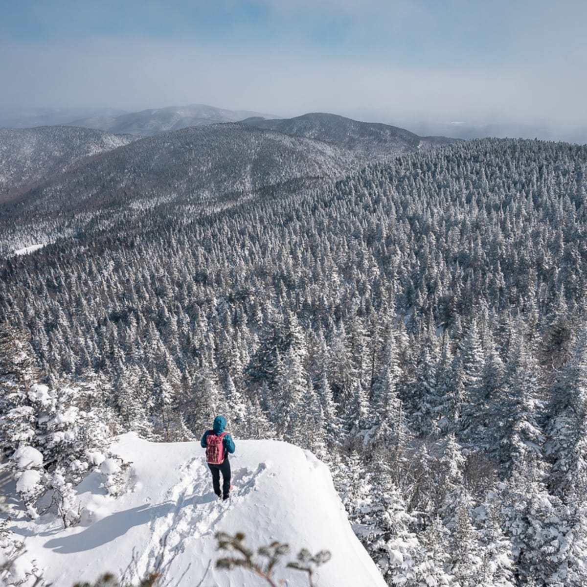 Hiker observing the horizon from a mountain peak in winter. 