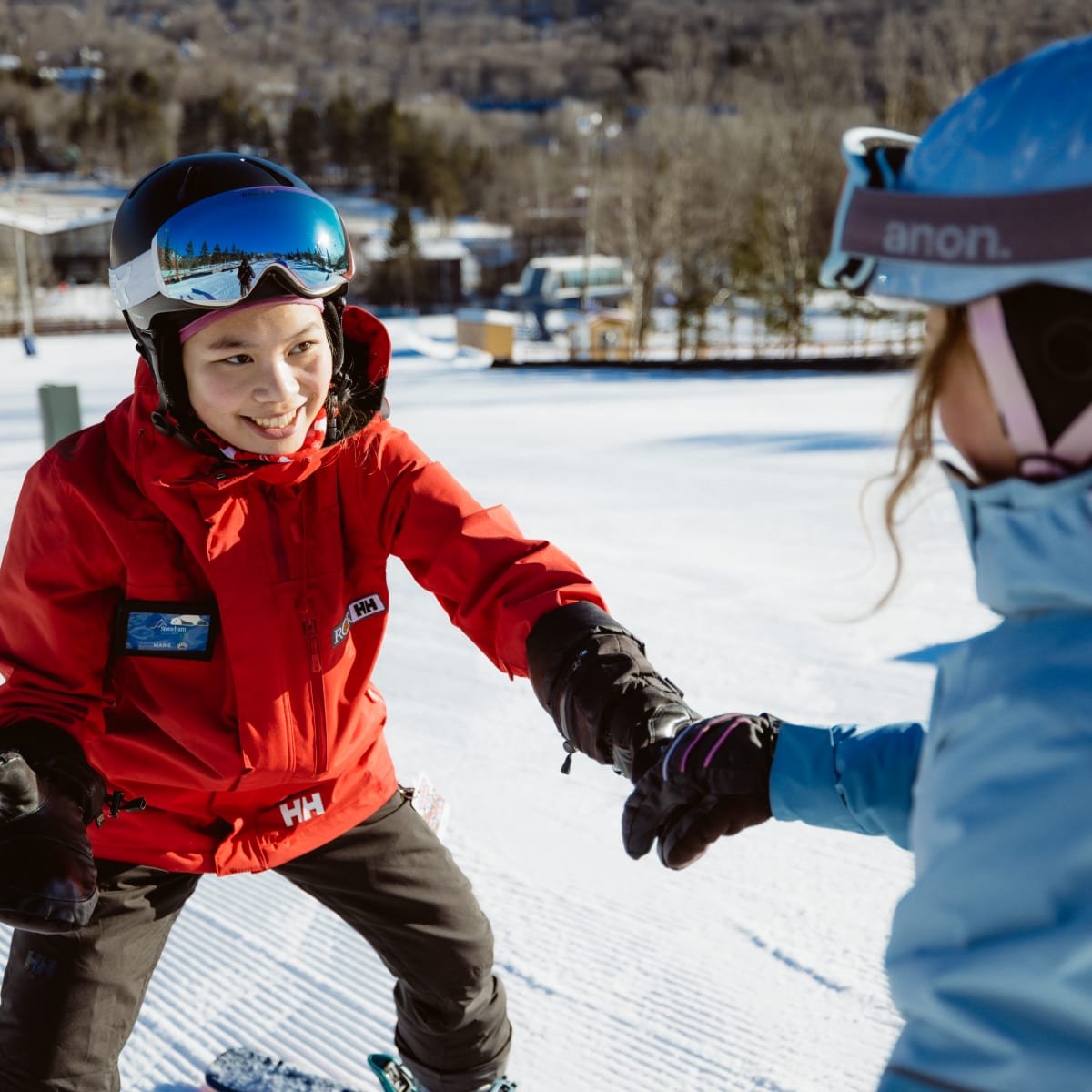 Monitrice tout sourire avec un élève sur les pistes.