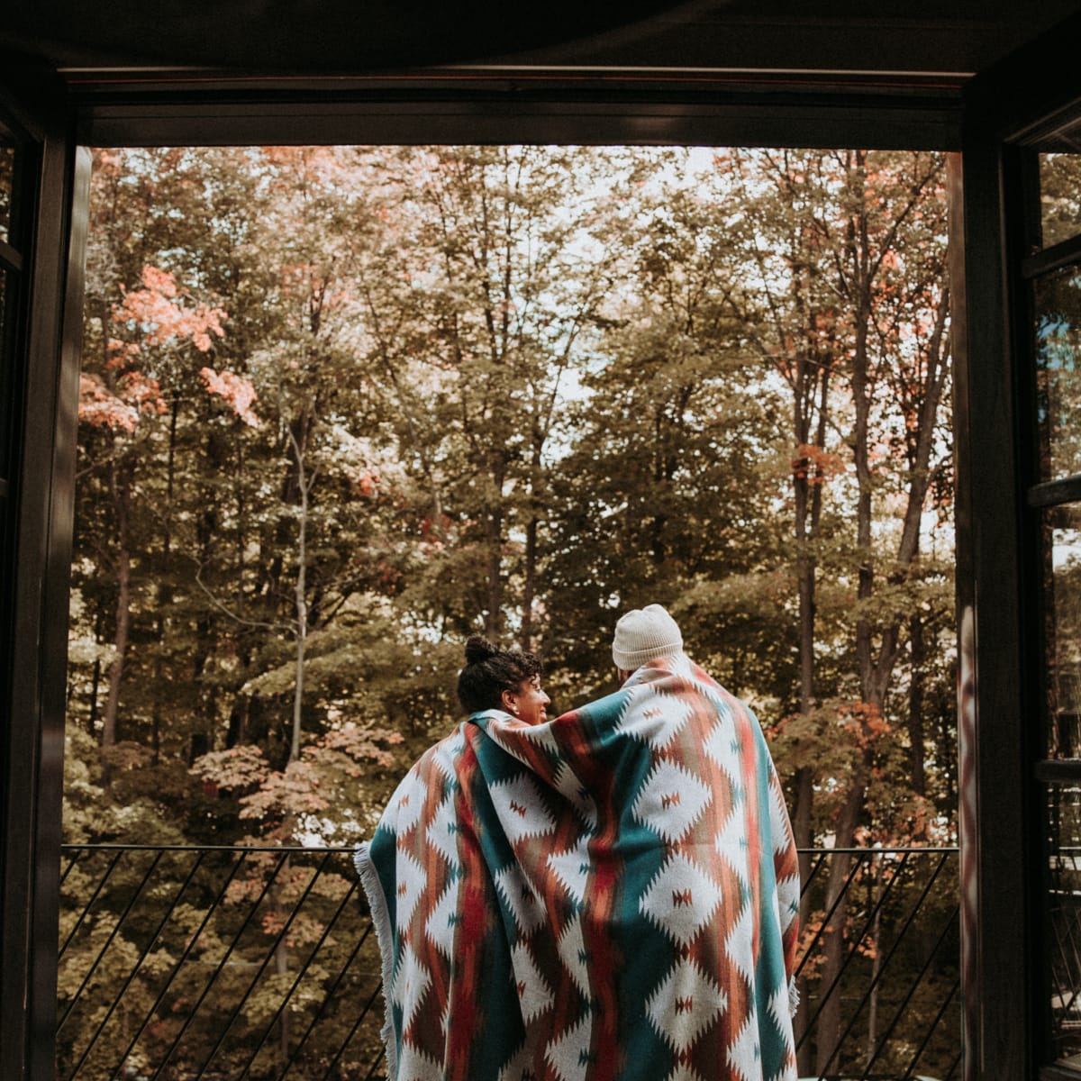 Couple in front of a forest in late fall.