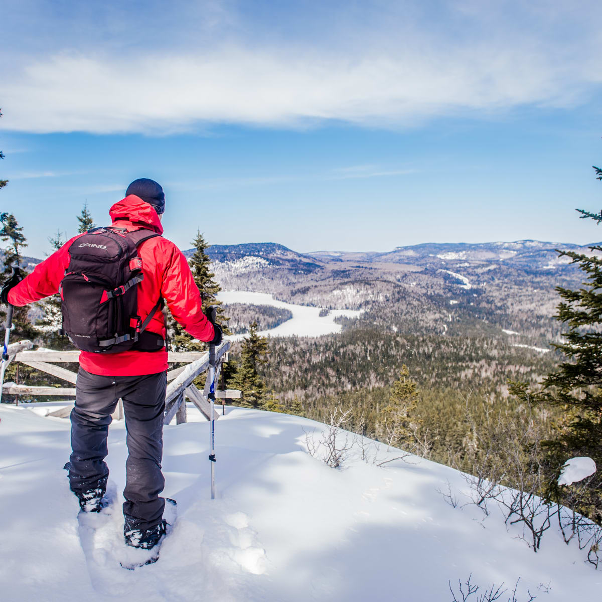 Snowshoer admiring the view at the top of snow-covered Mont Brassard.