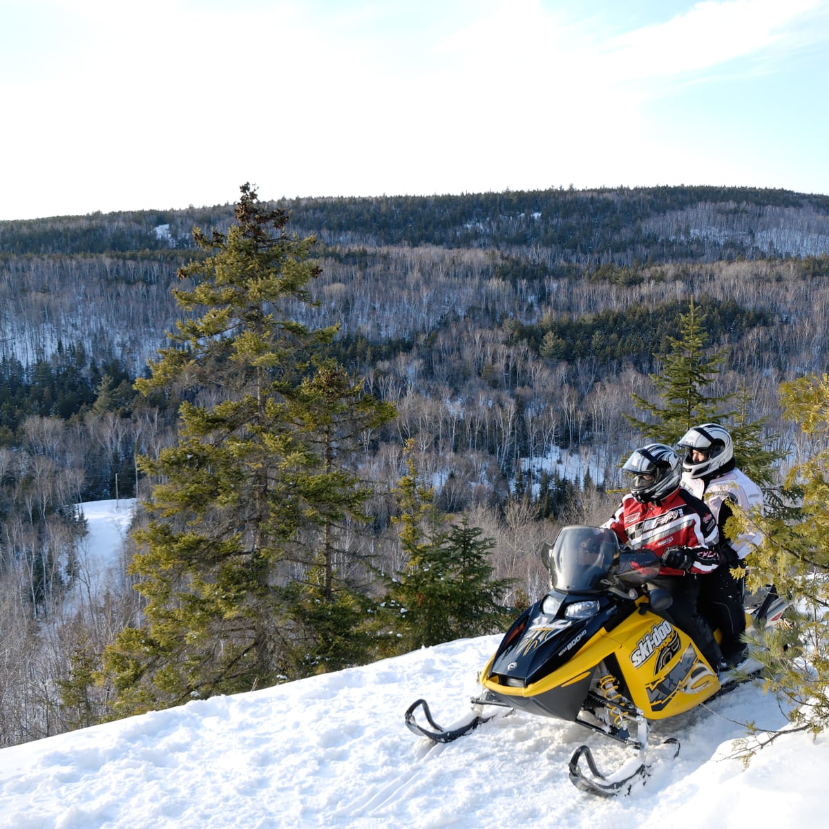 Deux personnes en motoneige devant les montagnes de la Mauricie
