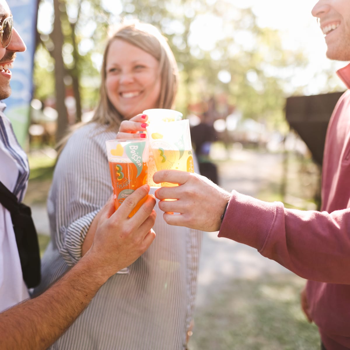 Three people making a toast with a glass of beer in hand.