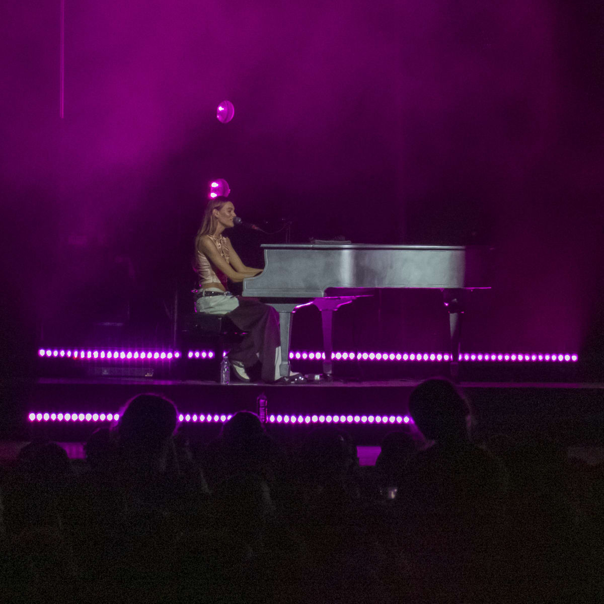 Charlotte Cardin at the piano on stage in the evening.