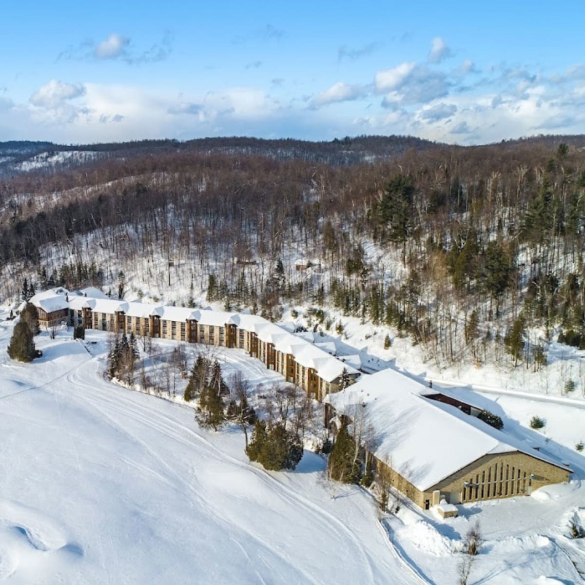 Aerial view of the hotel, surrounded by snow-covered fields and leafless trees.
