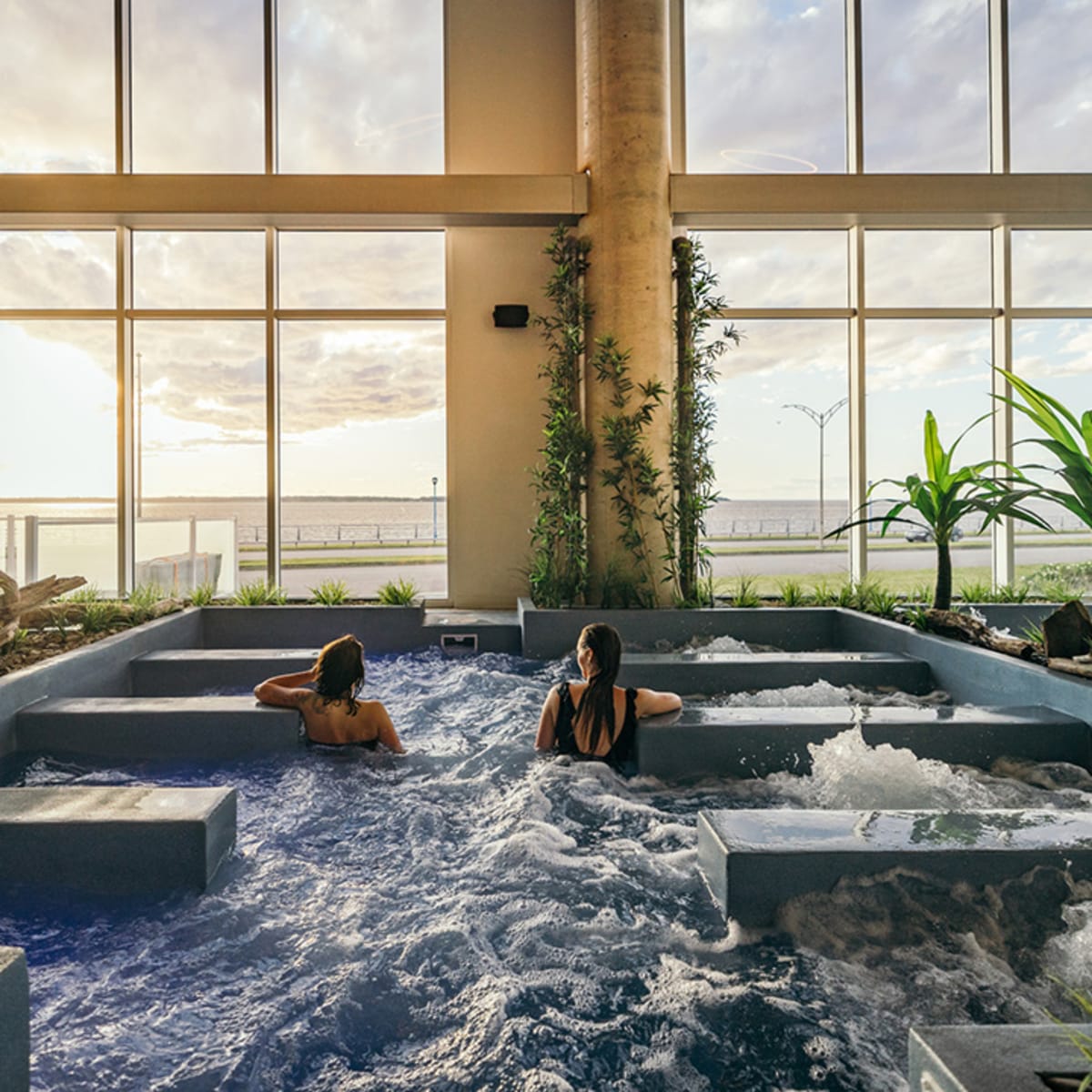 Two women in the baths at the Noah Spa looking out the bay window at the river.