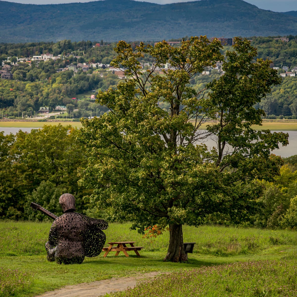 Sculpture représentant Félix Leclerc et paysage côtier de l'ile d'orléans.
