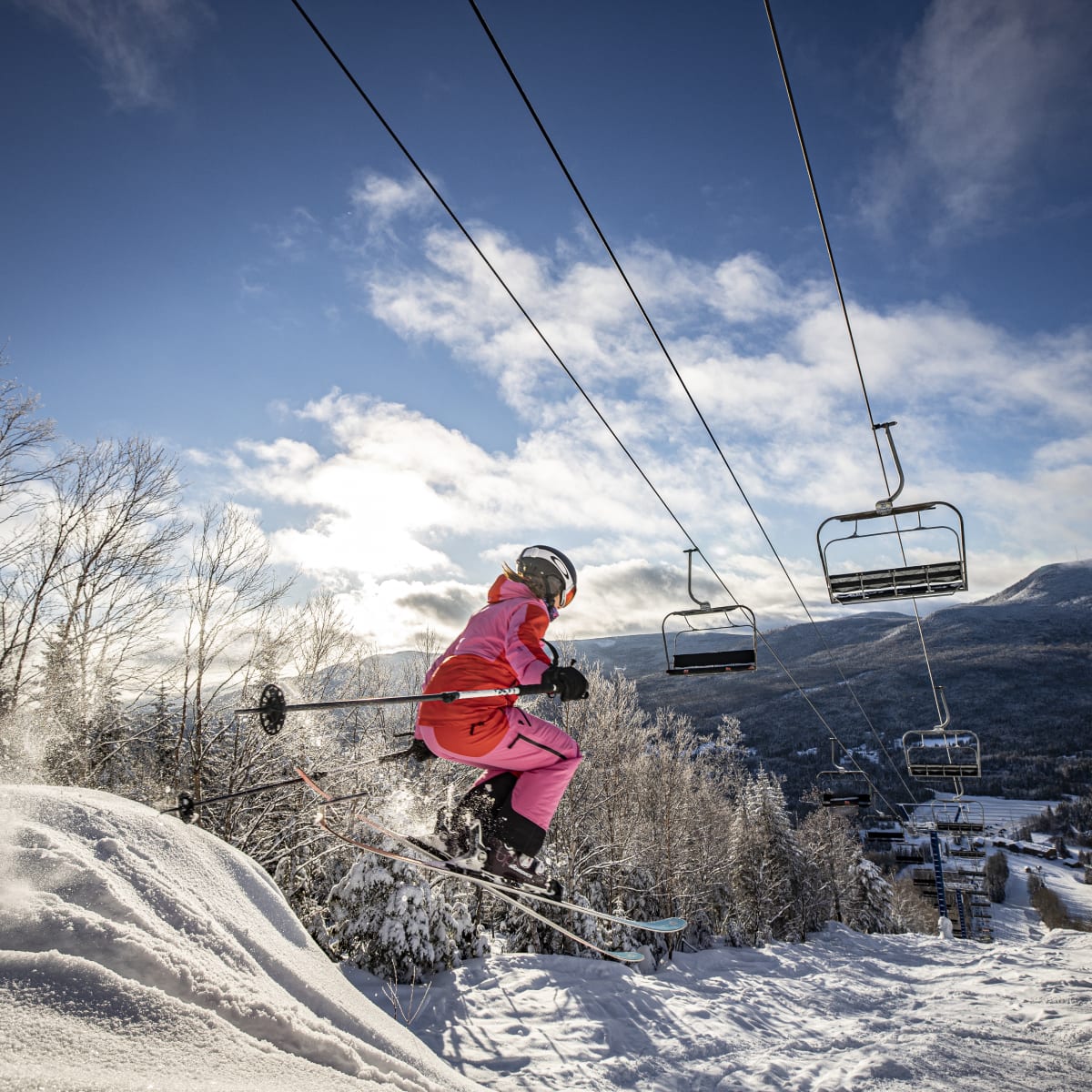 Skier making a jump underneath the ski lifts.